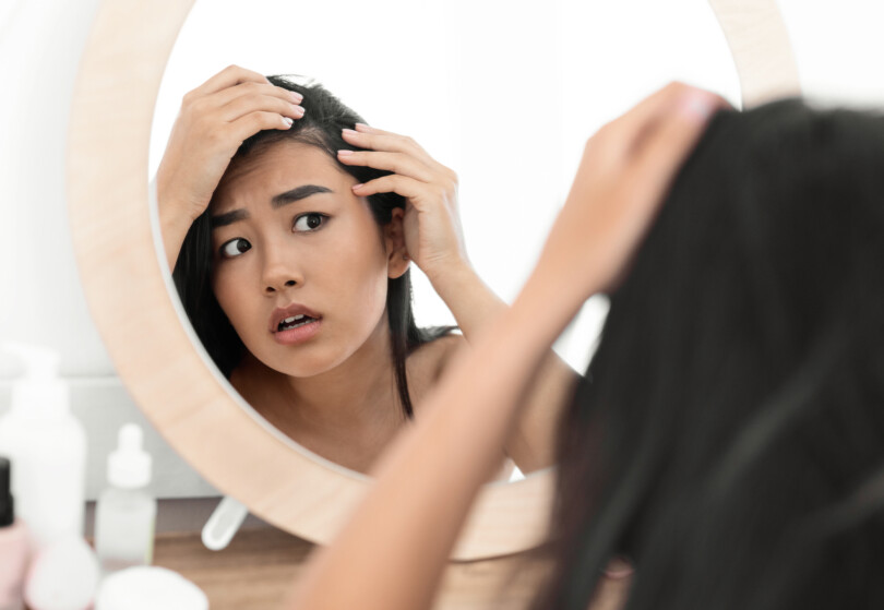Haarausfall bei Frauen - Frau schaut erschrocken in den Spiegel